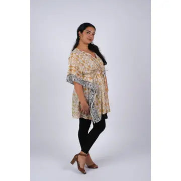 Woman in beige Aztec ikat print kaftan showing side profile and flowy dolman sleeves