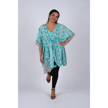 Woman wearing teal Aztec ikat print kaftan with gathered waist and dolman sleeves, front view