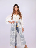 Woman wearing white Aztec boho crochet cover-up with tie-front and tassel details, front view