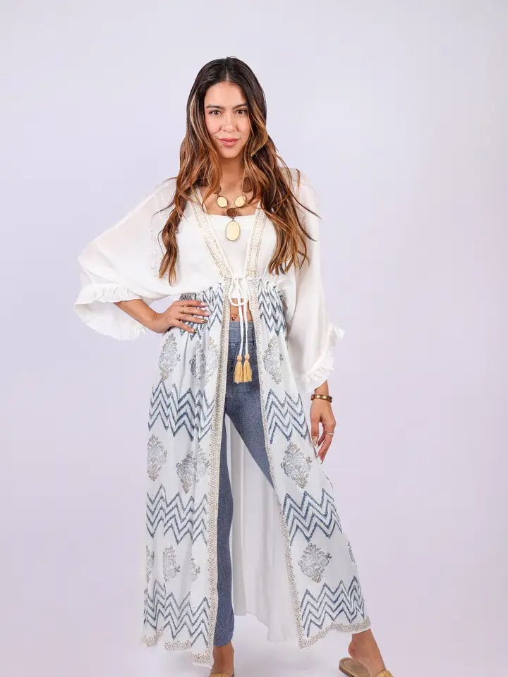 Woman wearing white Aztec boho crochet cover-up with tie-front and tassel details, front view