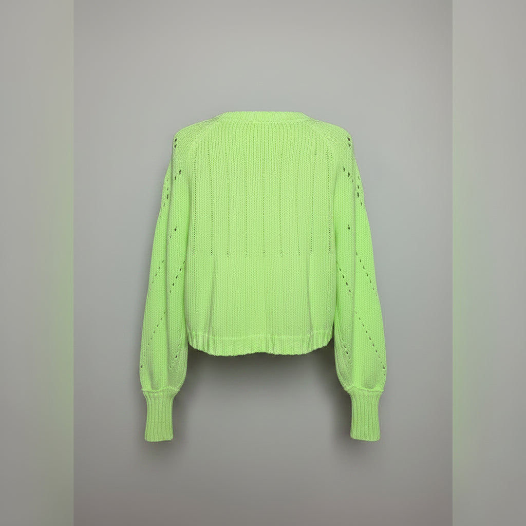 A neon yellow-green knit sweater with long sleeves and small cutout details, displayed on a black mannequin torso against a light wood plank background.