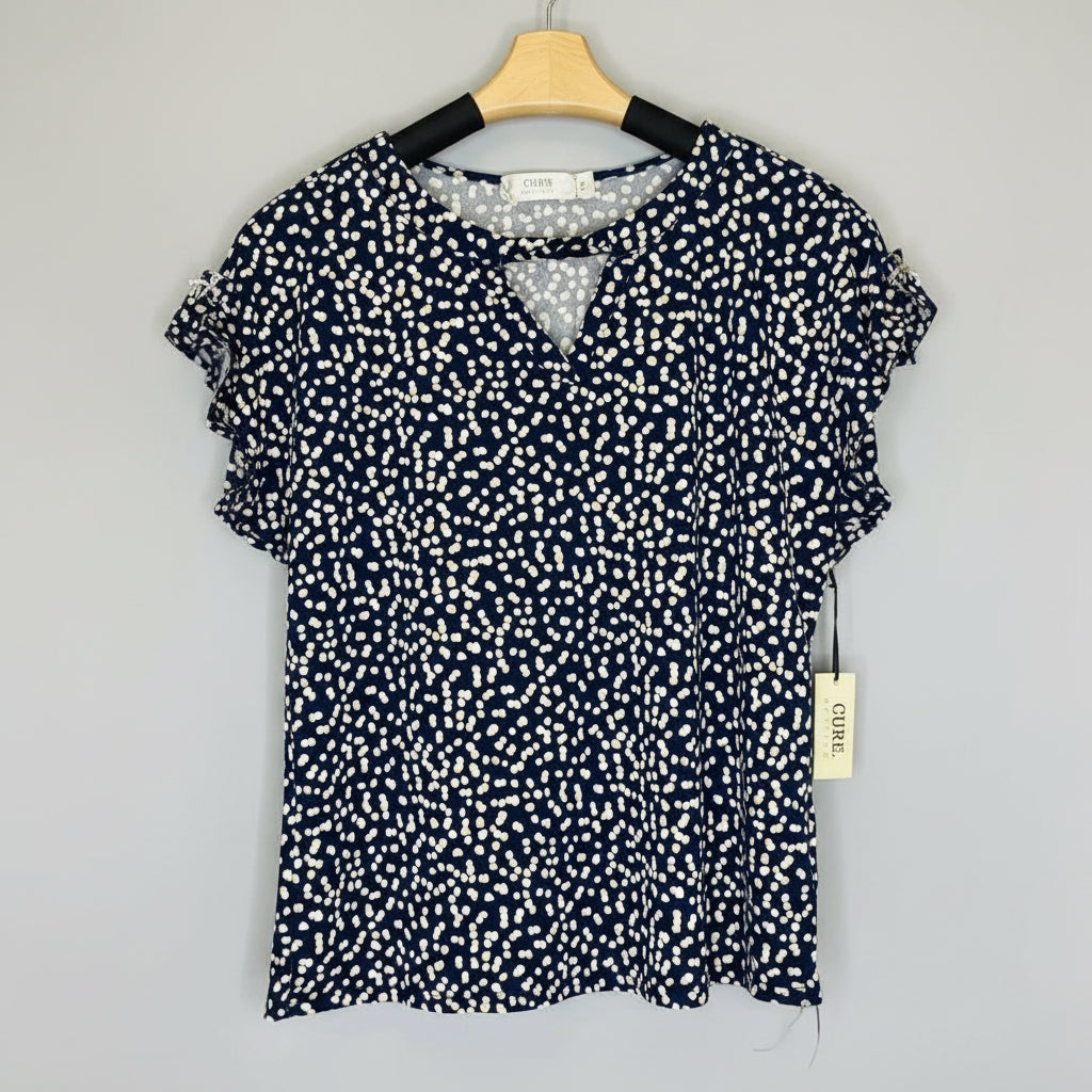 Navy blue blouse with white pattern on a hanger against a wooden background