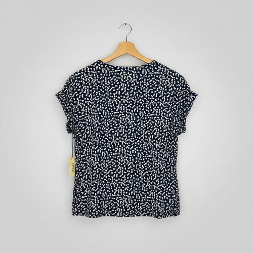 Navy blue shirt with white pattern on a wooden hanger against a wooden background