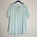 A light mint green Nike short-sleeve athletic t-shirt hanging on a dark hanger against a rustic whitewashed wood plank background.