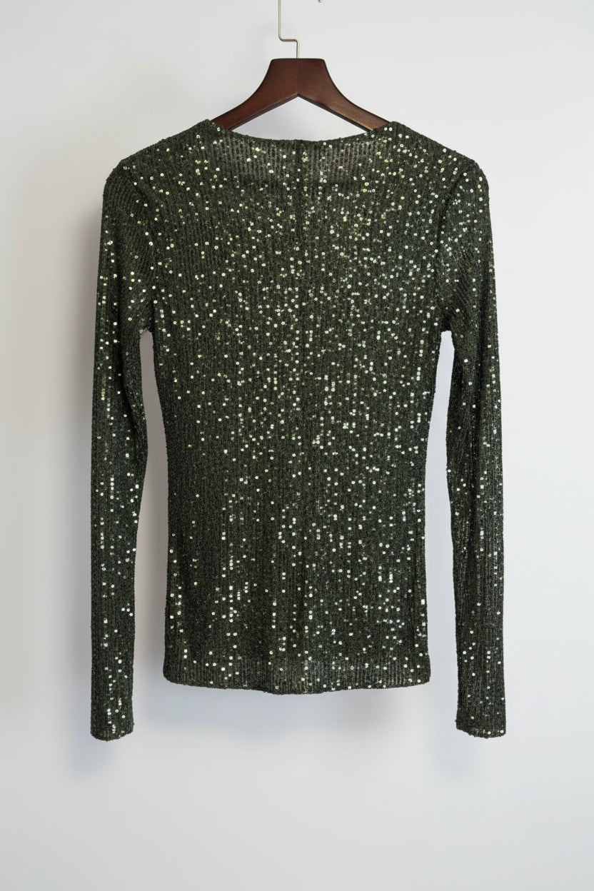 Green sequin top on a hanger against a white background