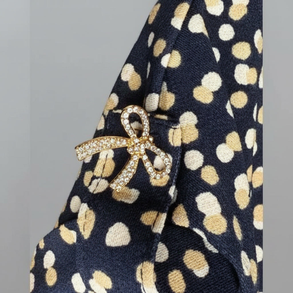 Navy fabric with gold polka dots and a decorative bow brooch.