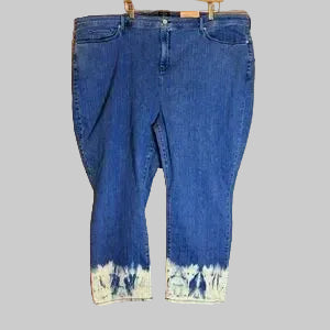 Blue jeans with a tie-dye bottom section on a wooden background