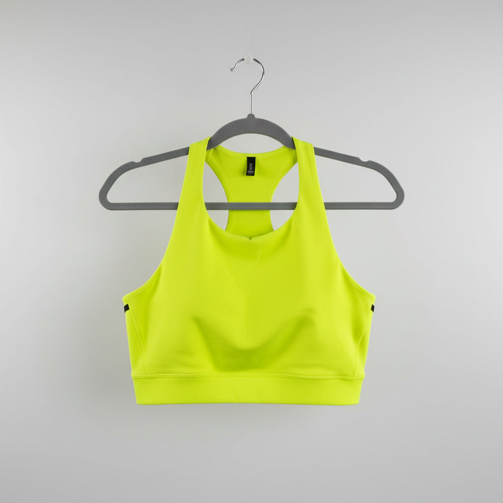 A bright neon yellow athletic sports bra with a scoop neck, hanging on a gray hanger against a light wood background.