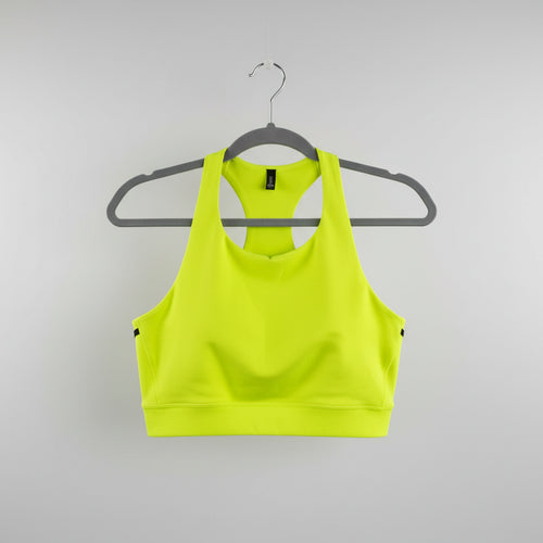 A bright neon yellow athletic sports bra with a scoop neck, hanging on a gray hanger against a light wood background.
