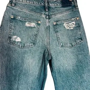 Close-up of a pair of blue jeans with distressed details on the back pockets.